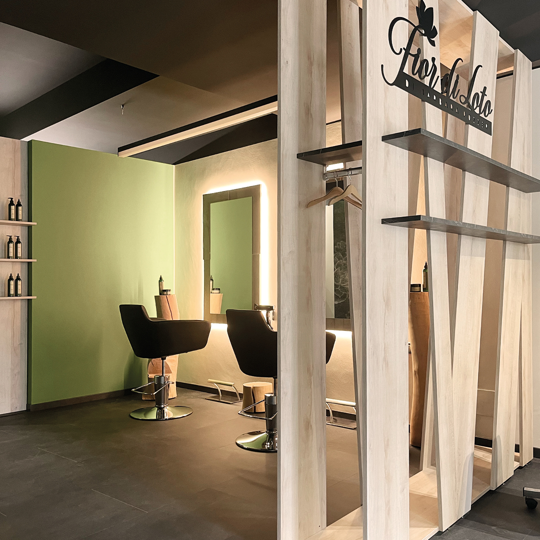 Immagine di due postazioni dell'area stilistica con poltrone nere, pareti verdi, specchi grandi e rettangolari e mobilio decorativo in legno 